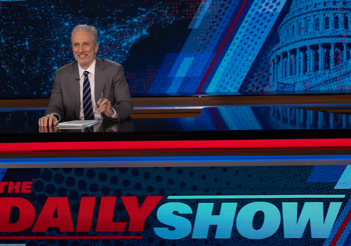 Jon Stewart behind the desk hosting 'The Daily Show'