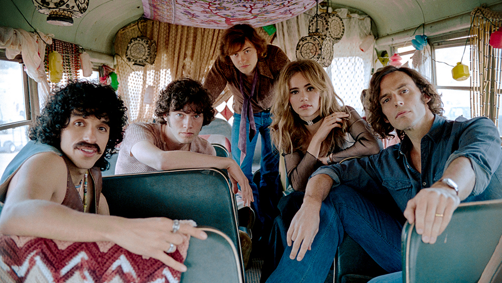 The members of Daisy Jones and the Six arranged in a tour bus looking towards the camera in an album cover pose.