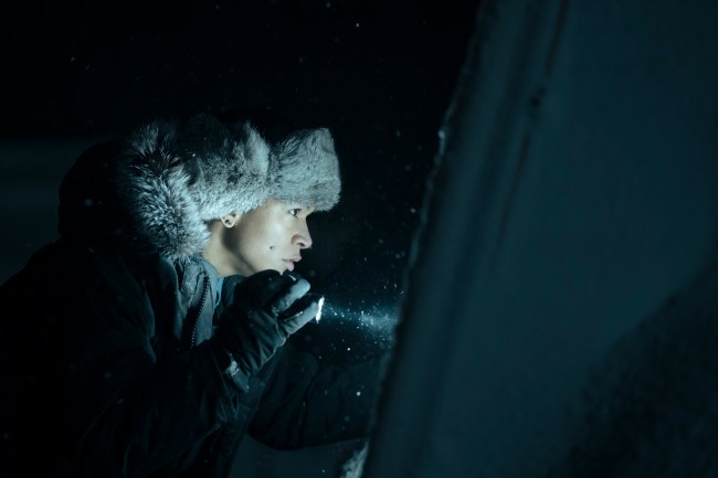 Kali Reis as Detective Navarro peers at something out of frame with a flashlight as snow falls around her in "True Detective: Night Country" 