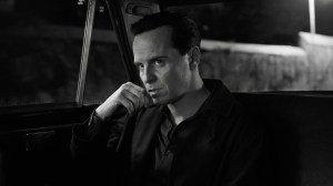 Black-and-white still of a man sitting in the back of a car; Andrew Scott in and as 'Ripley.'