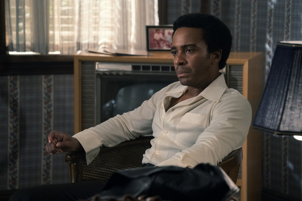 André Holland as Black Panther Huey Newton in 'The Big Cigar,' shown here sitting in a chair wearing a white button-down