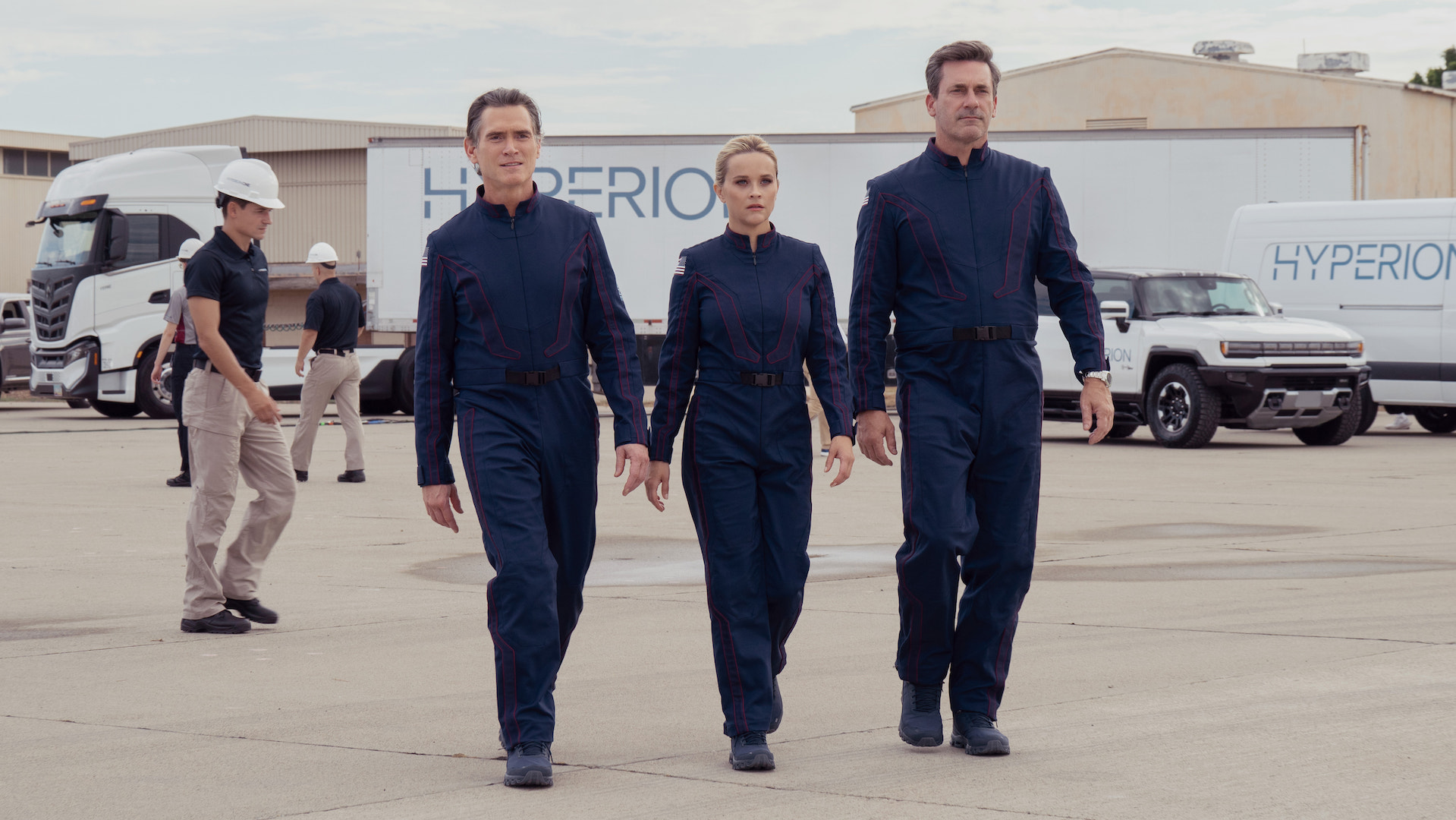 Two men and a woman in full bodysuits walking across tarmac; still from The Morning Show